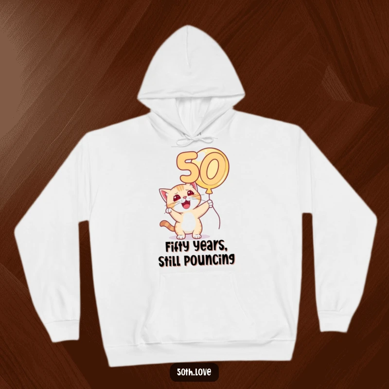 Funny 'Cat 50th Birthday' Hoodie: A playful cat with a sly grin bats at a floating golden number 50 balloon.